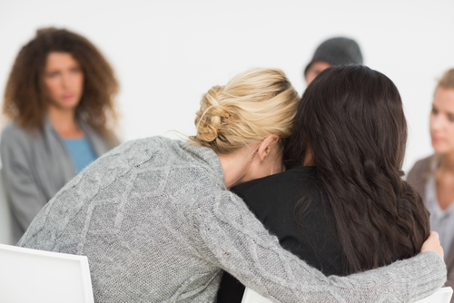 Women receiving hug in support group