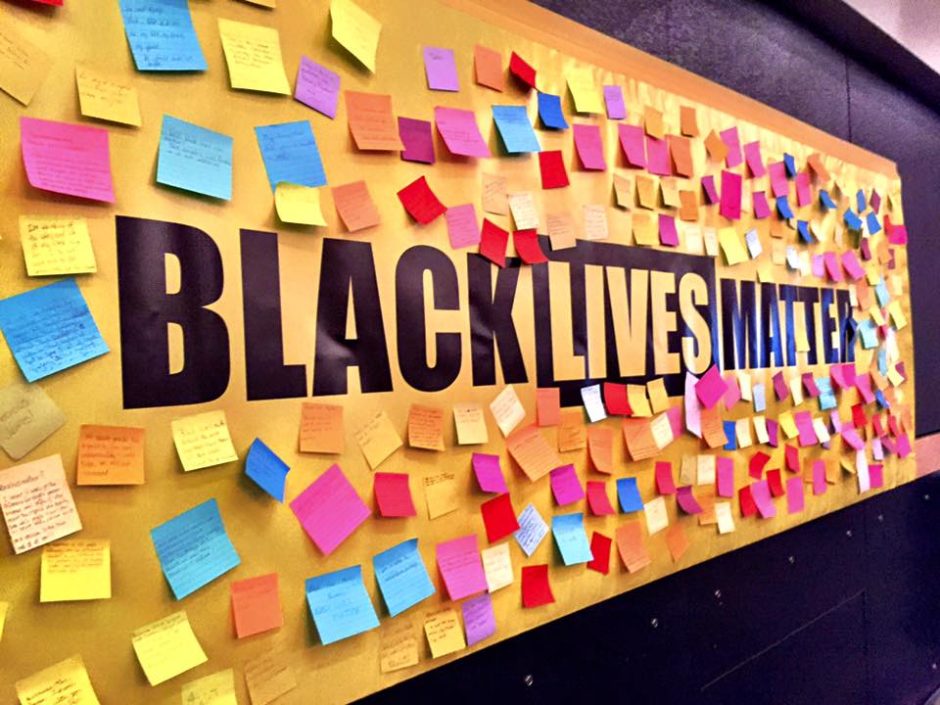 Banner that reads "Black Lives Matter" covered with post-its of varied colors and writing that is too small to read.