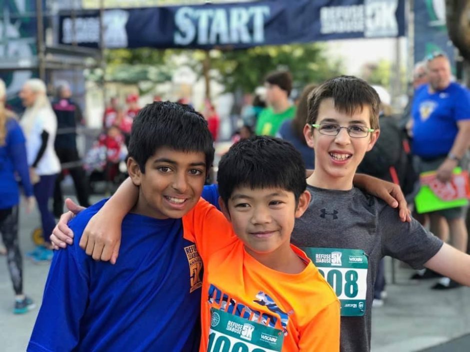 Three boys smiling under a "Refuse To Abuse 5K START" banner