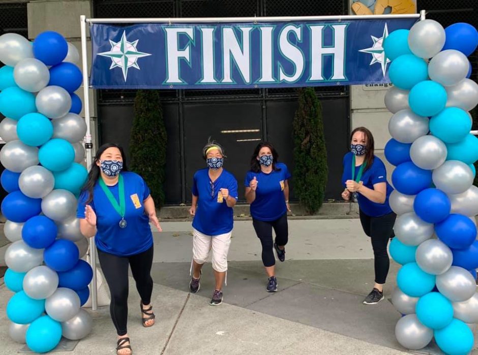 Four women standing at the 2020 Refuse To Abuse 5K Finish Line. They are all wearing masks and starting to run towards the camera.