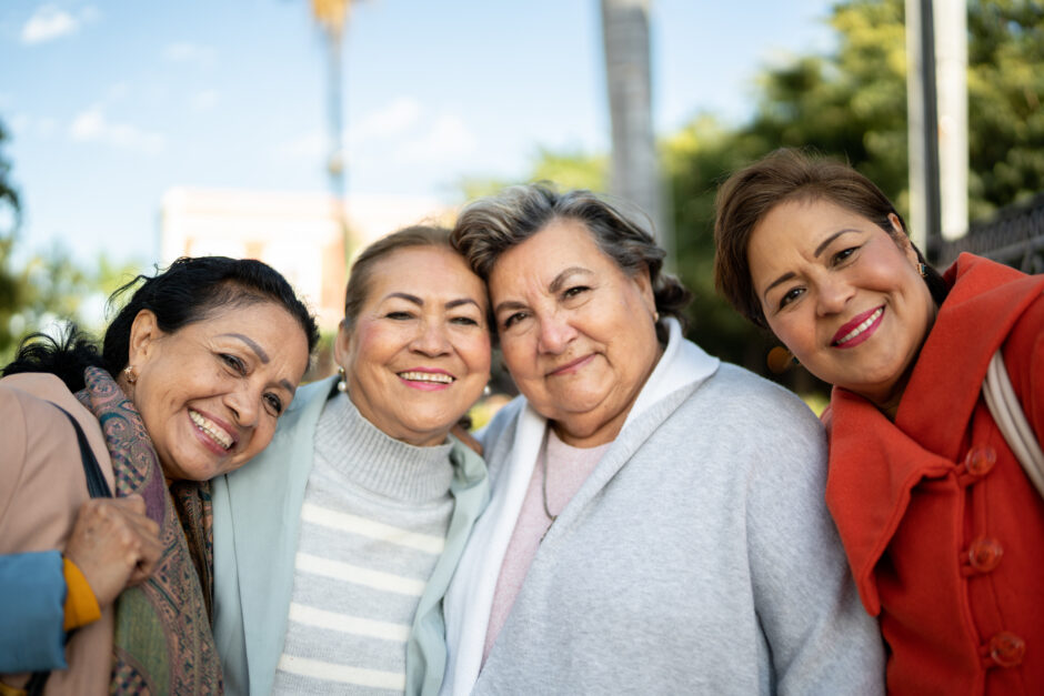 Group of four women smiling together.